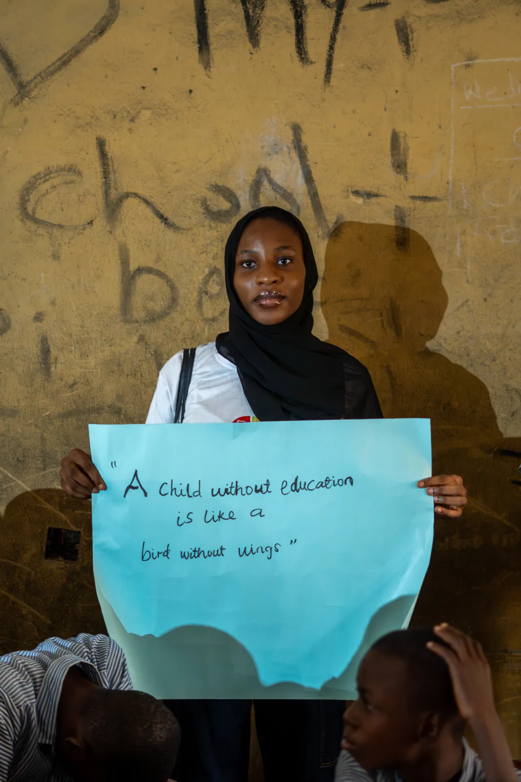 A student holding a handwritten message about education